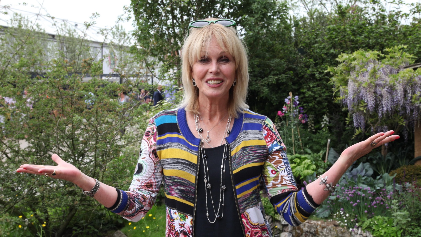 joanna lumley standing in a garden holding her arms out