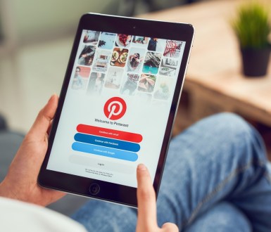 A person holds a tablet showing the Pinterest log-in page