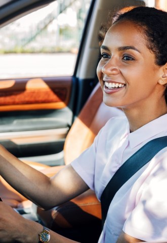 A woman smiling while she drives a car